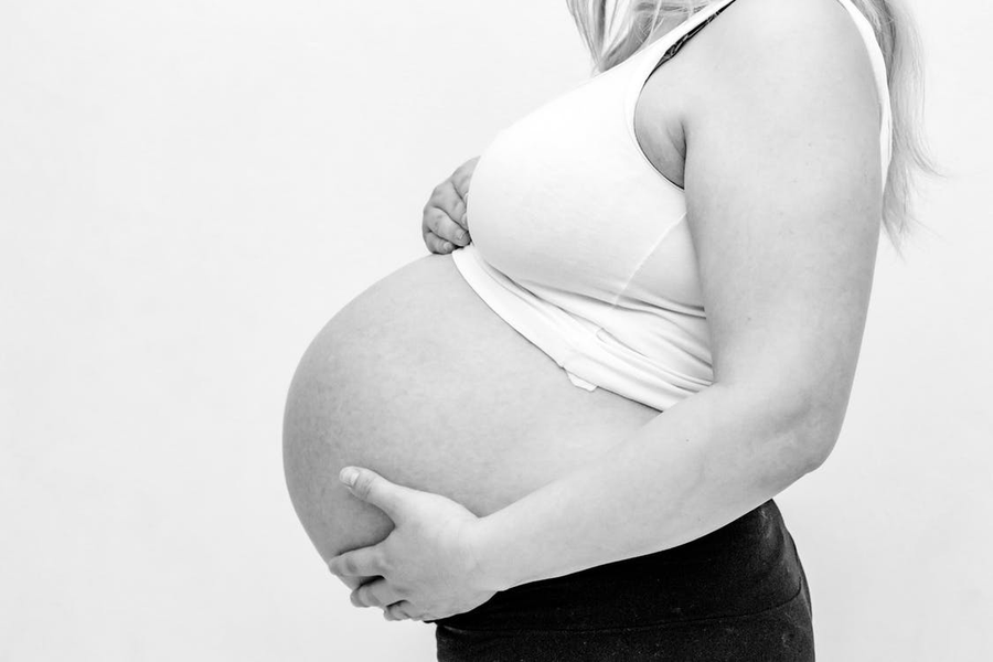  A black and white image depicting a pregnant woman holding her belly.