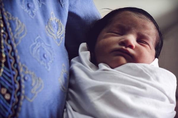 Sleeping swaddled baby in mother's arms 