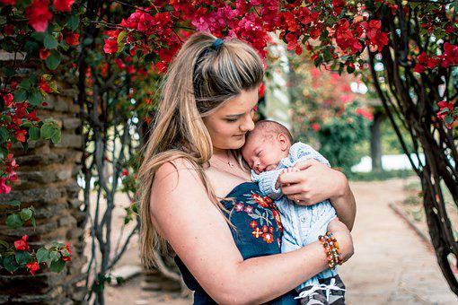 a new mother cradling her newborn outside next to flowers