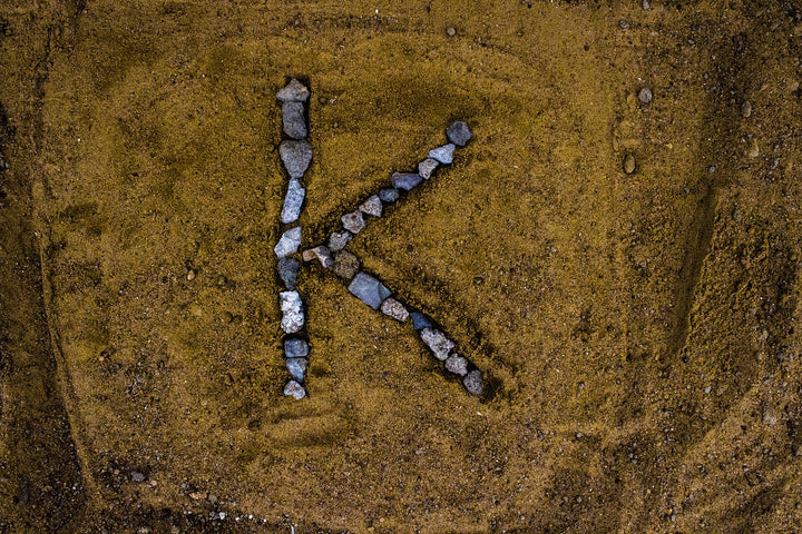 the letter K spelled with rocks in the sand