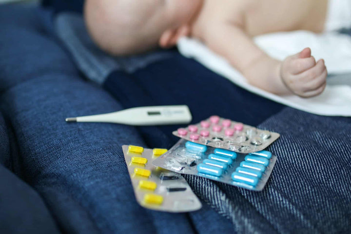 Baby with thermometer and pills