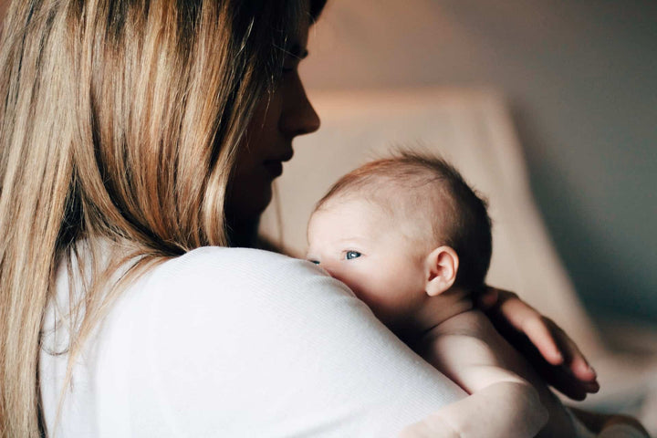 Sad baby in mother’s arms