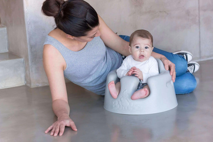 mother next to baby in a floor seat