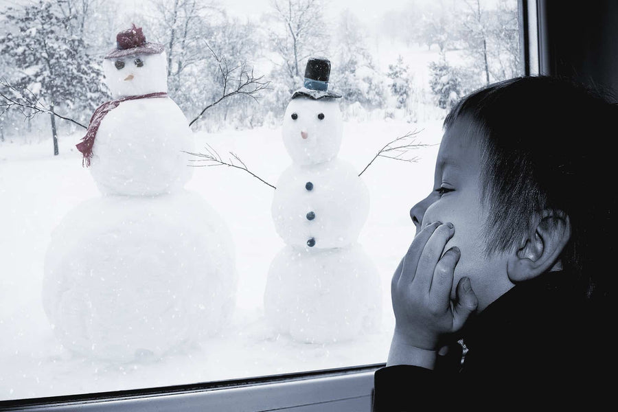 Child looking out at two snowmen