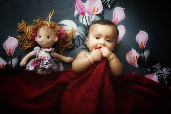  a baby laying next to a doll