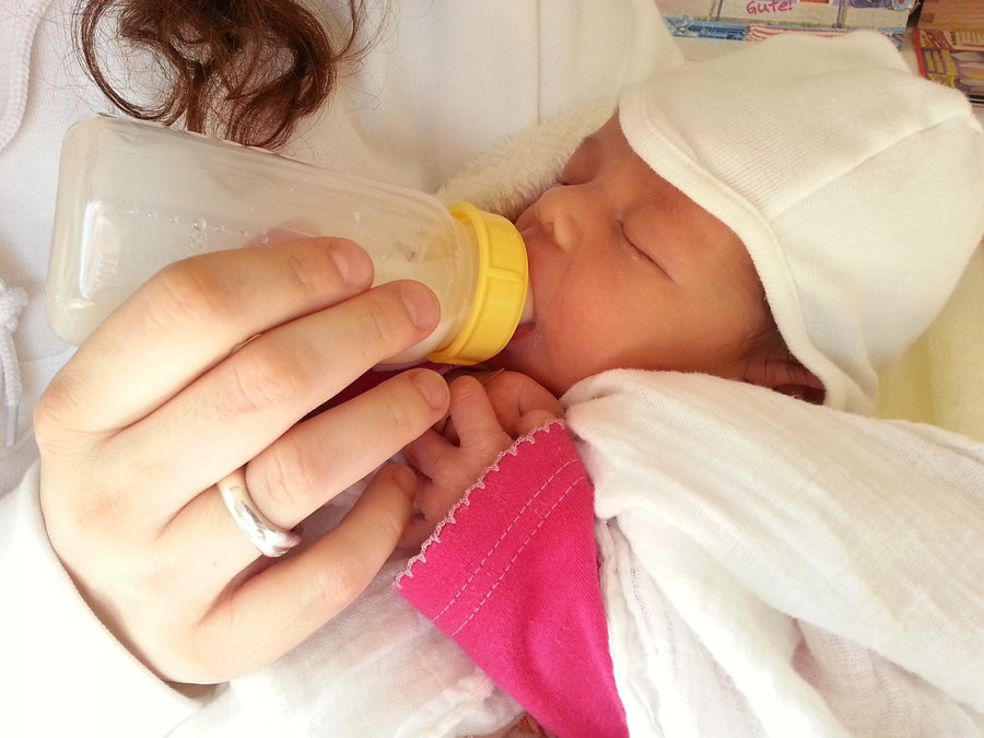 a newborn being fed a bottle