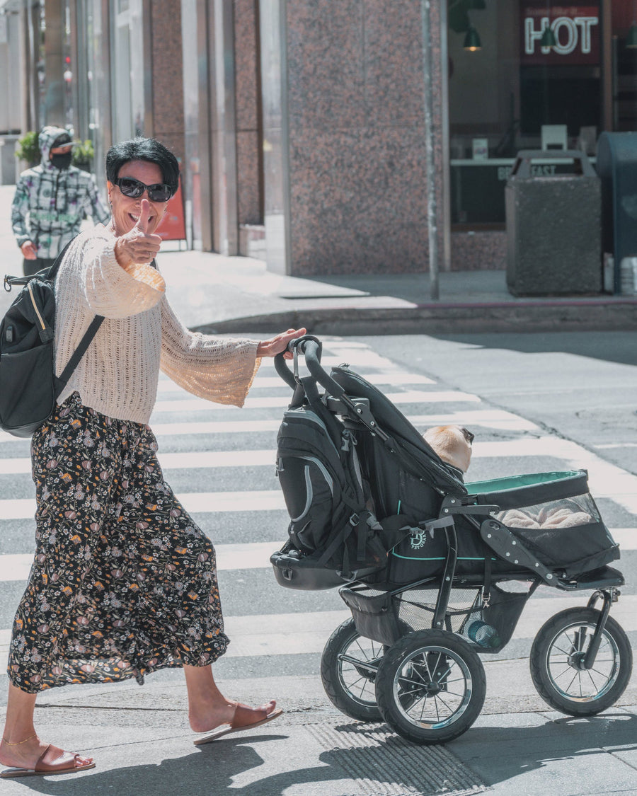 a mother swearing a diaper bag pushing a baby in a stroller