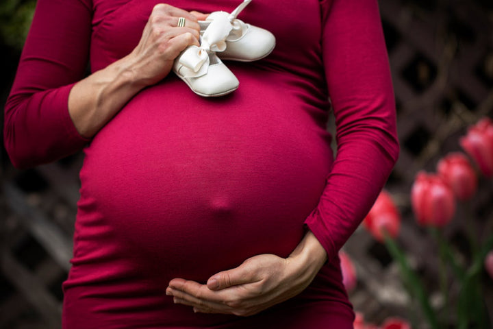 pregnant mom with baby shoes