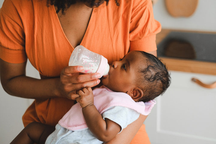 Woman holds baby in her arms while she feeds them