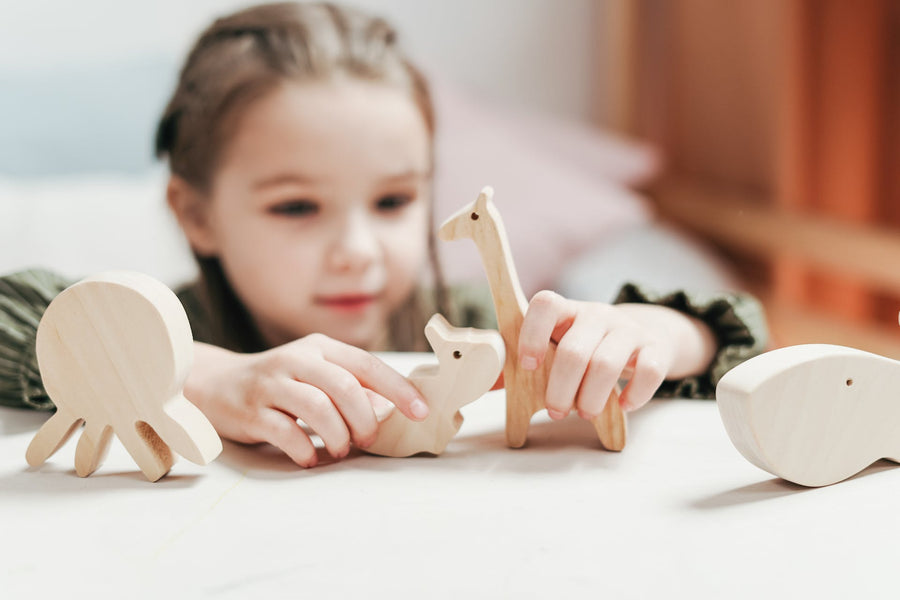 A young girl plays with wooden dinosaurs