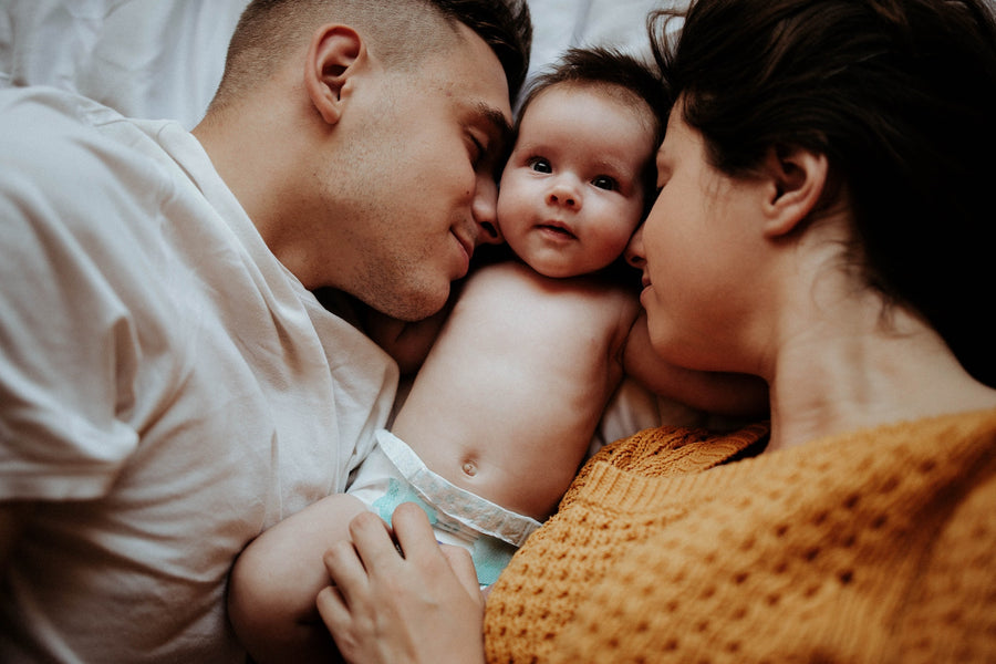 parents in a bed with their baby