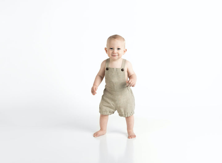 A baby stands in front of a white background