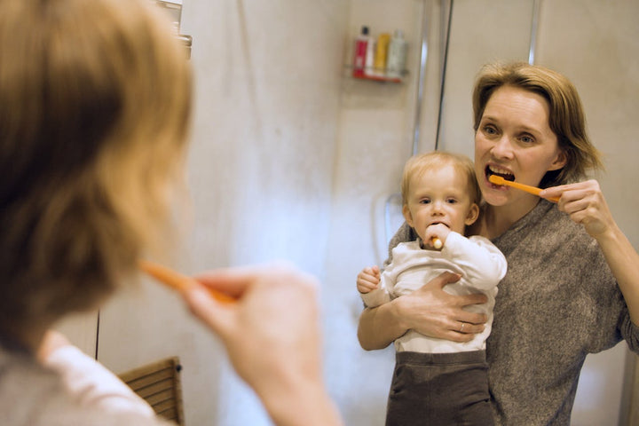 baby brushing teeth with mom