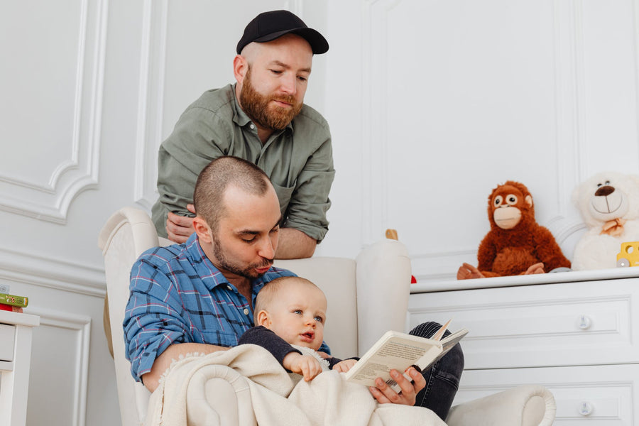 two adults reading a LGBTQ baby book to a baby