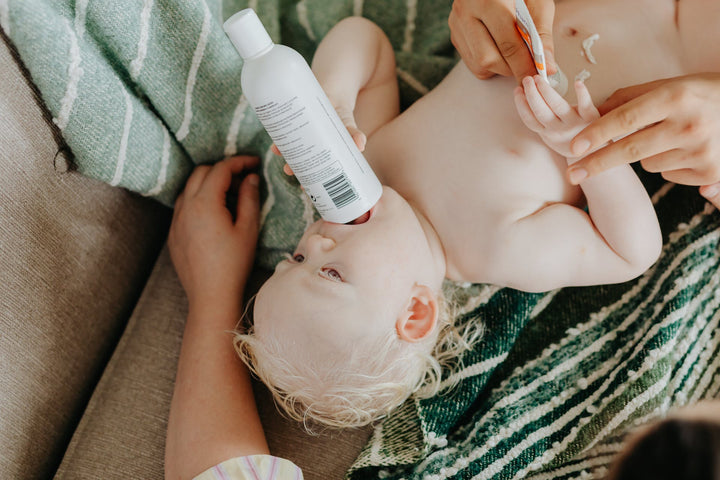 Baby plays with a bottle while getting changed