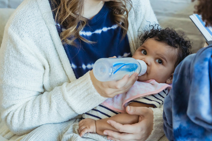A mom feeds her baby with a bottle