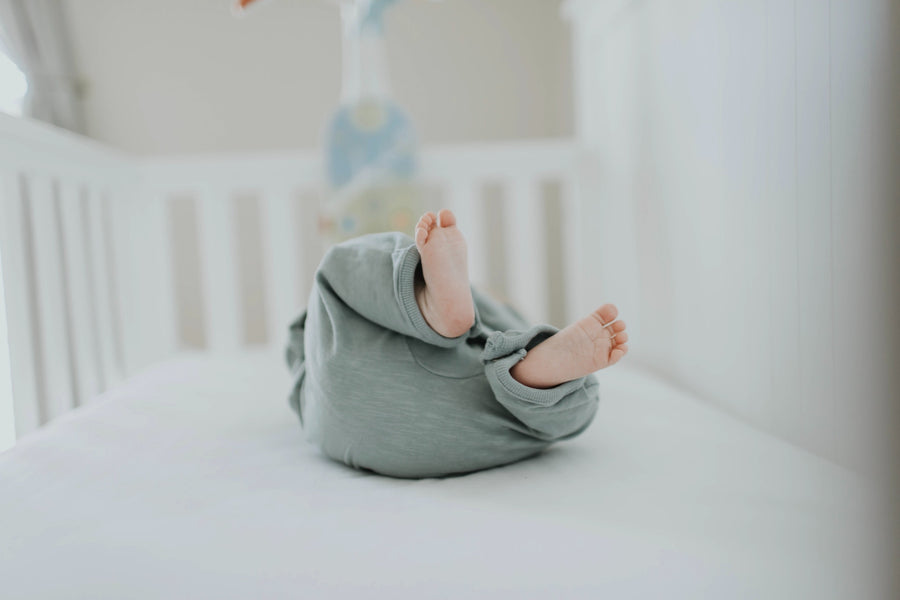 Baby lays in a crib with their feet up
