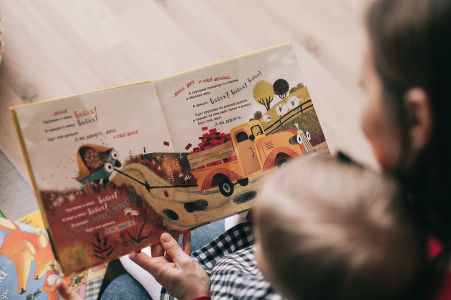 Mom holds her baby while reading a children's book