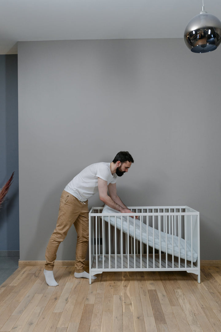 a father installing a crib mattress