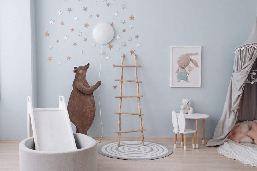 A blue nursery with a bear painted on the wall