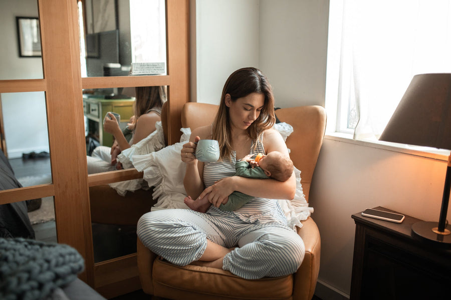 a mother holding her newborn baby and a cup of coffee