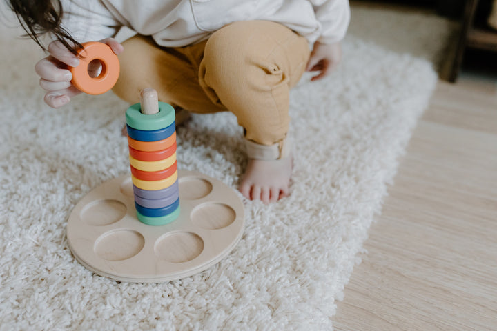 a toddler using a wooden stacking toy