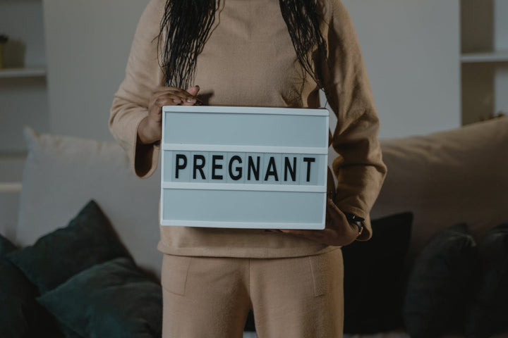A woman holds a sign that reads “Pregnant”