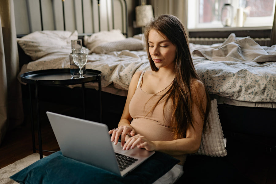  pregnant woman typing on a laptop