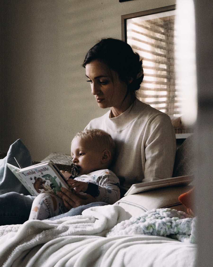 a mother reading to her baby in bed